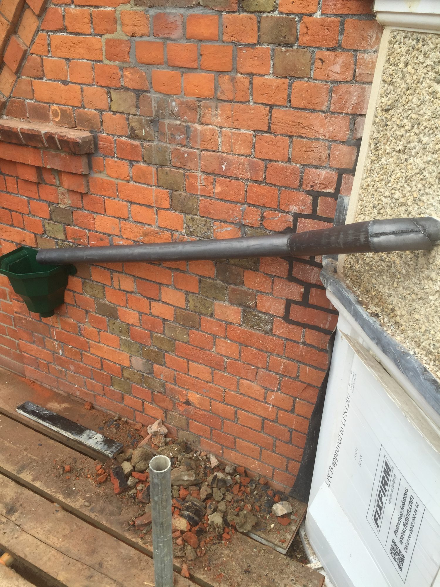 Refurbished lead pipe running horizontally along the brick wall, with a neat joint visible near the right-hand side