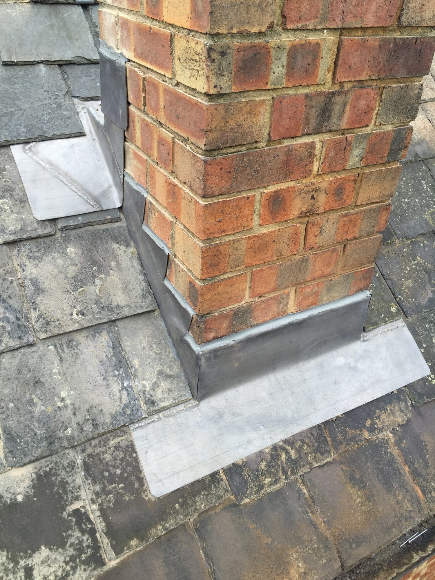 Close-up view of the brick chimney with finished lead weathering extending around the base and integrated with the surrounding slate roof