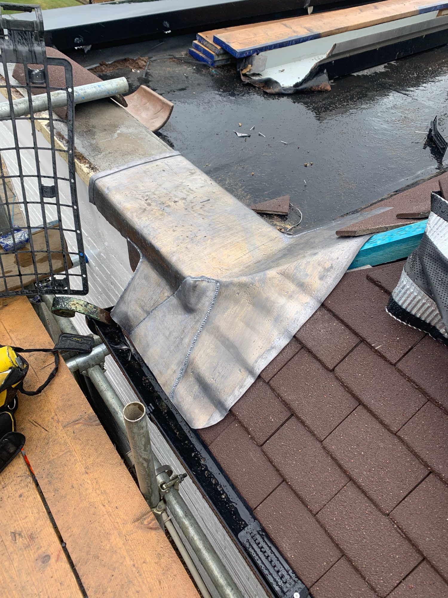 Close-up of formed leadwork at the junction between the roof surfaces, with the lead dressed around the edge and adjoining guttering visible below