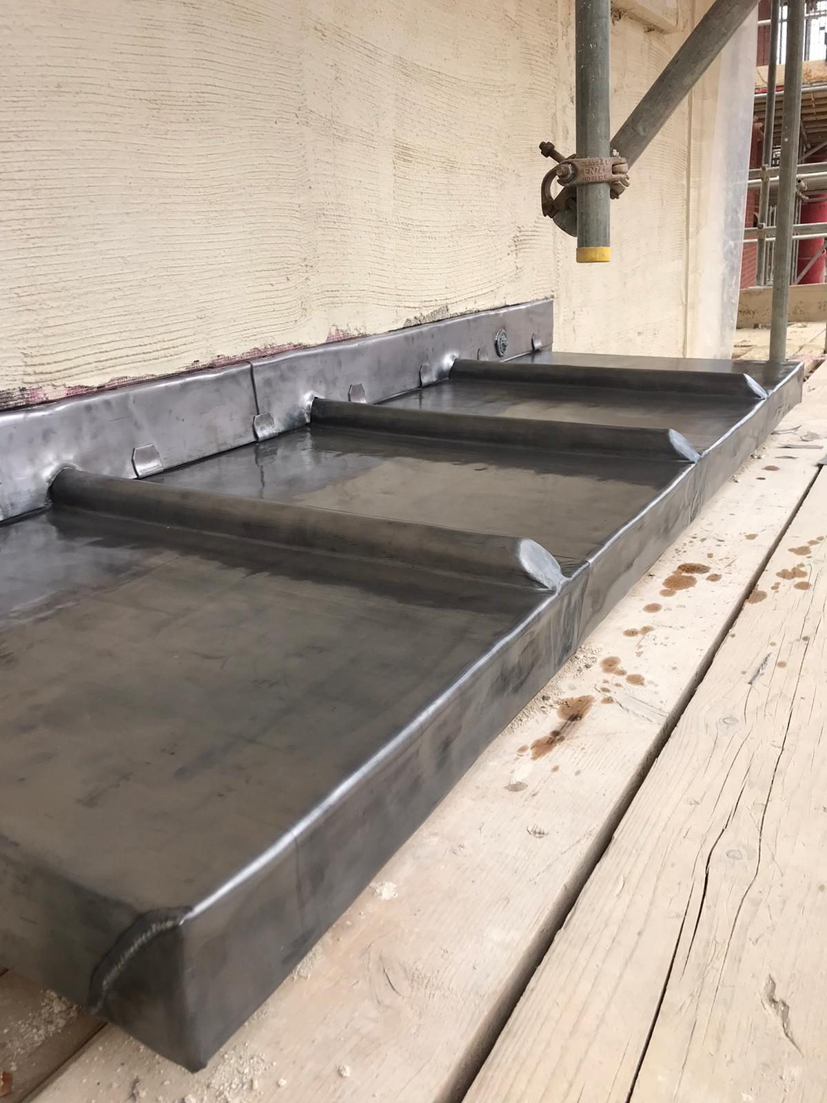 Completed - The completed lead roof section showing neatly formed raised seams, edge detailing and lead flashing against the rendered wall