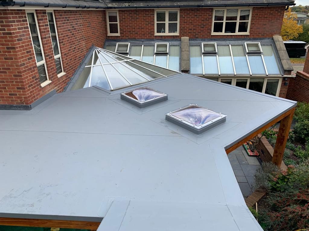 Completed - The completed single-ply flat roof with two rooflights, showing the smooth membrane finish and neat detailing around the adjoining property