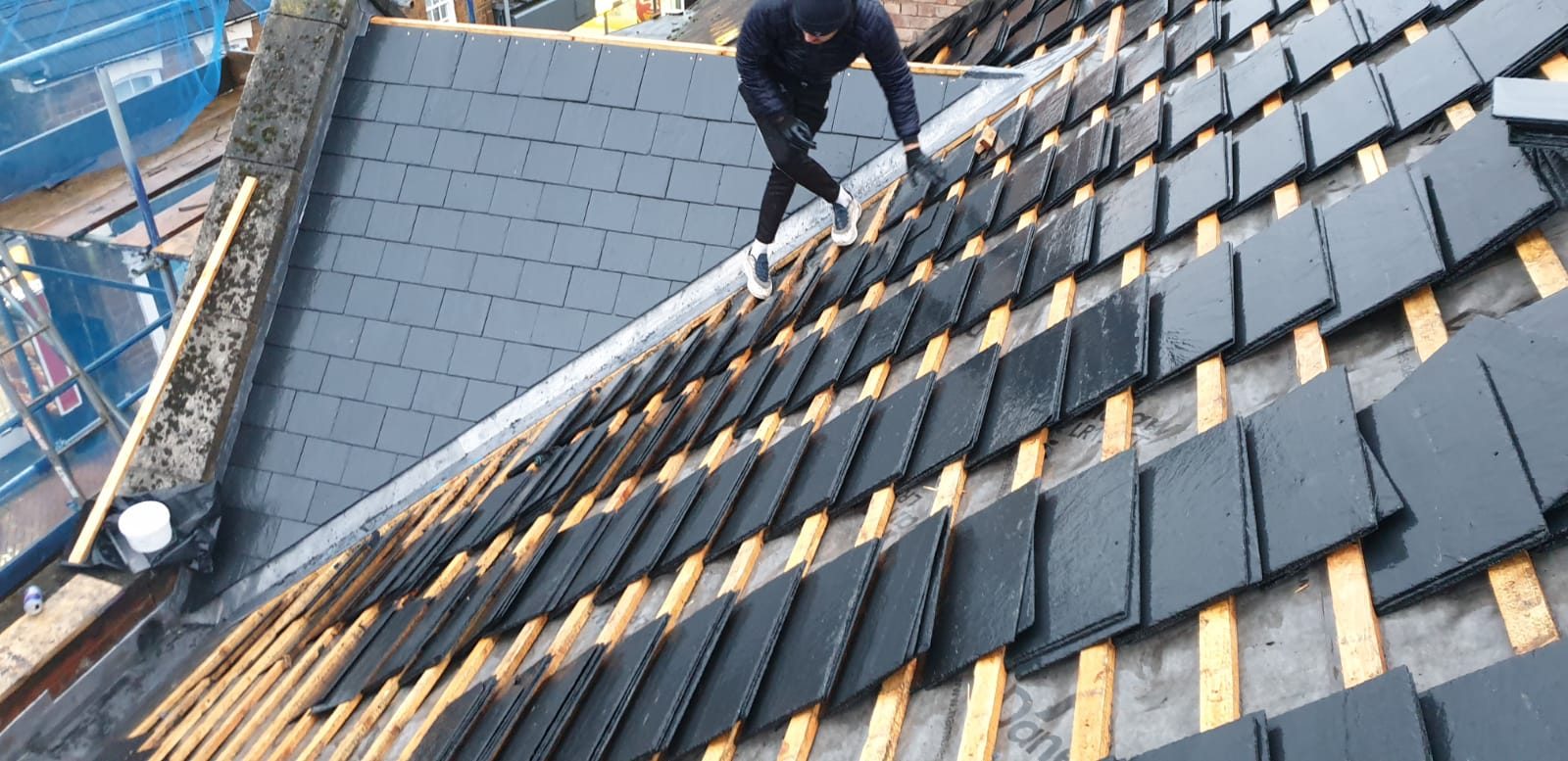 During - New slate roof tiles being installed over roofing membrane and battens during the large slate roof replacement