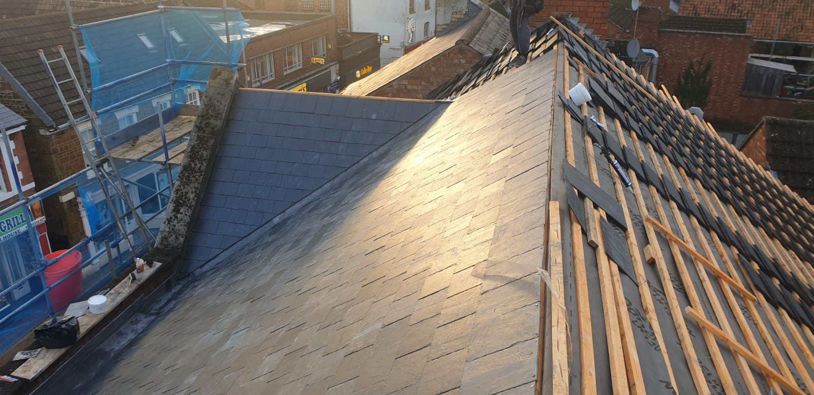 During - New slate tiles being installed over roofing membrane and timber battens during the large slate roof replacement