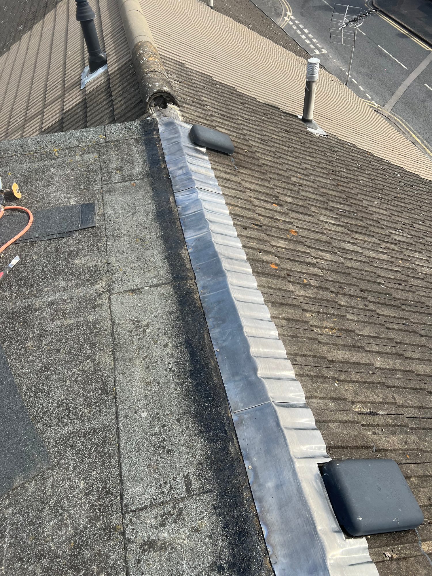 During - The roof during refurbishment showing new lead flashing being fitted between the flat roof and tiled pitched roof