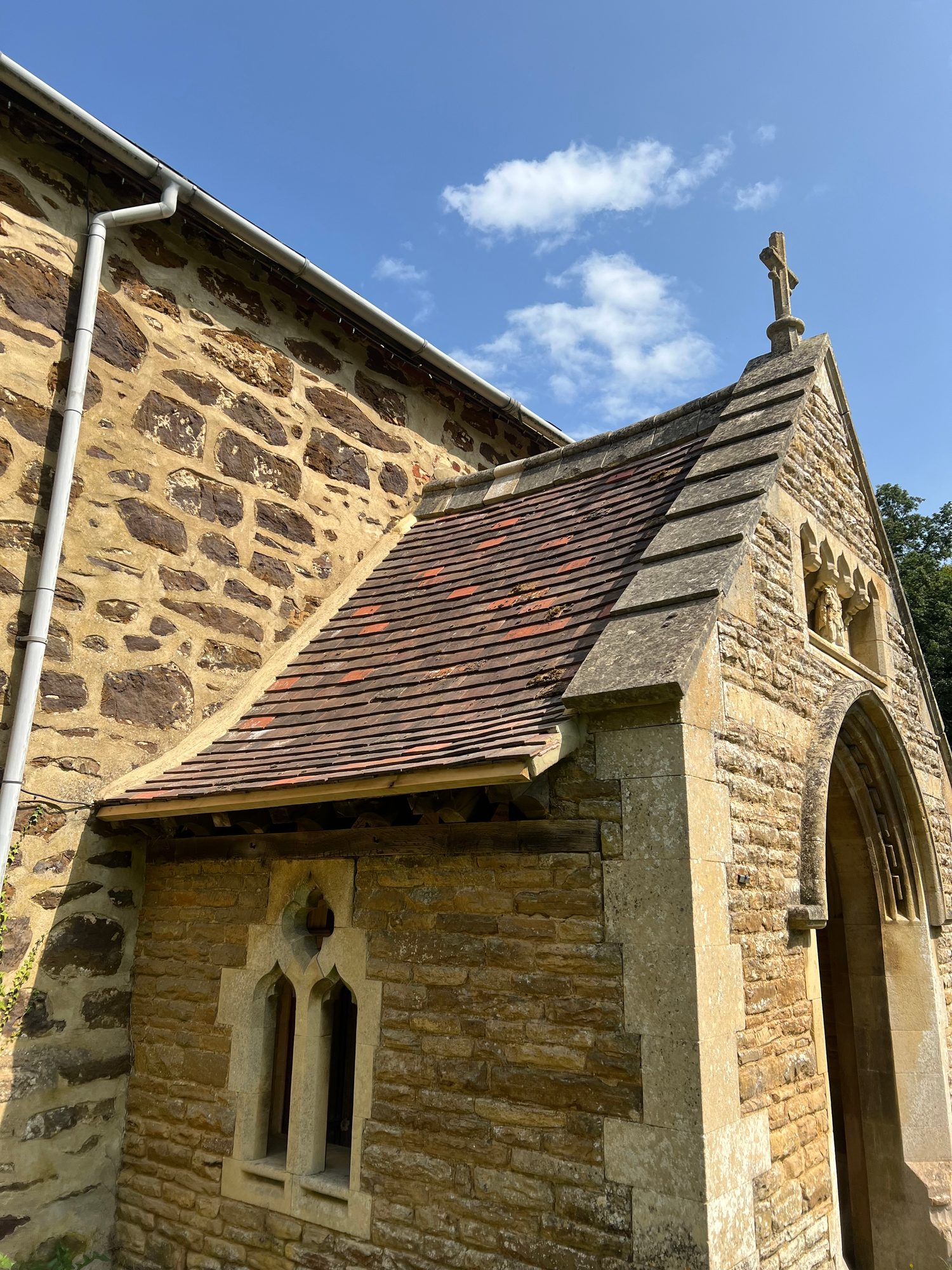 Completed - The completed stone building showing the restored tiled roof, natural stonework, arched doorway, decorative window and cross detail