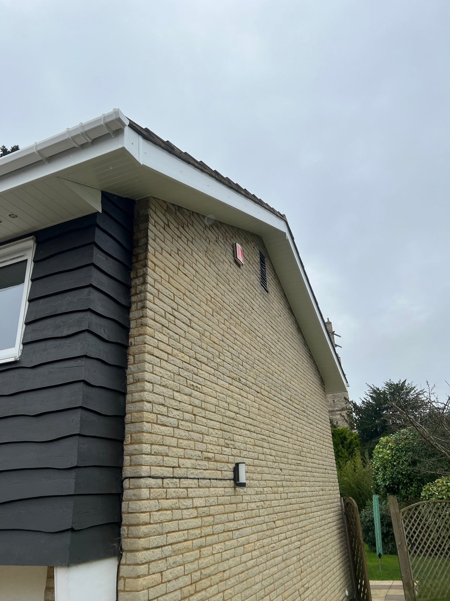 Completed - The completed brickwork and dark exterior cladding with white soffits, fascia and guttering along the side of the property