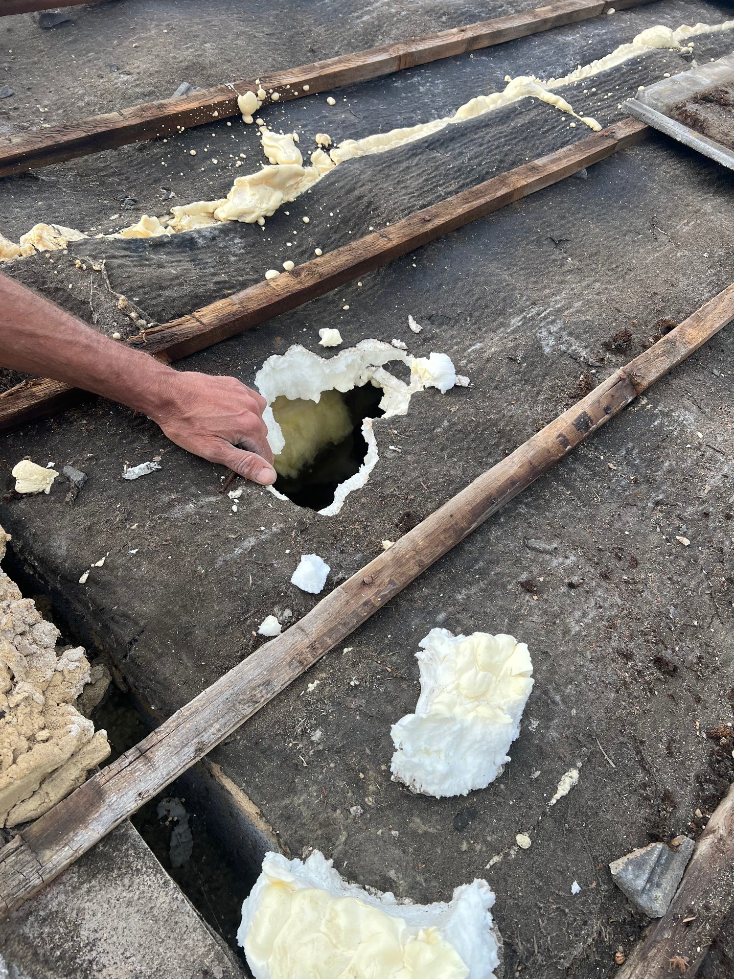 Close-up of the roof surface with timber battens, exposed foam insulation and an opening in the roof structure visible