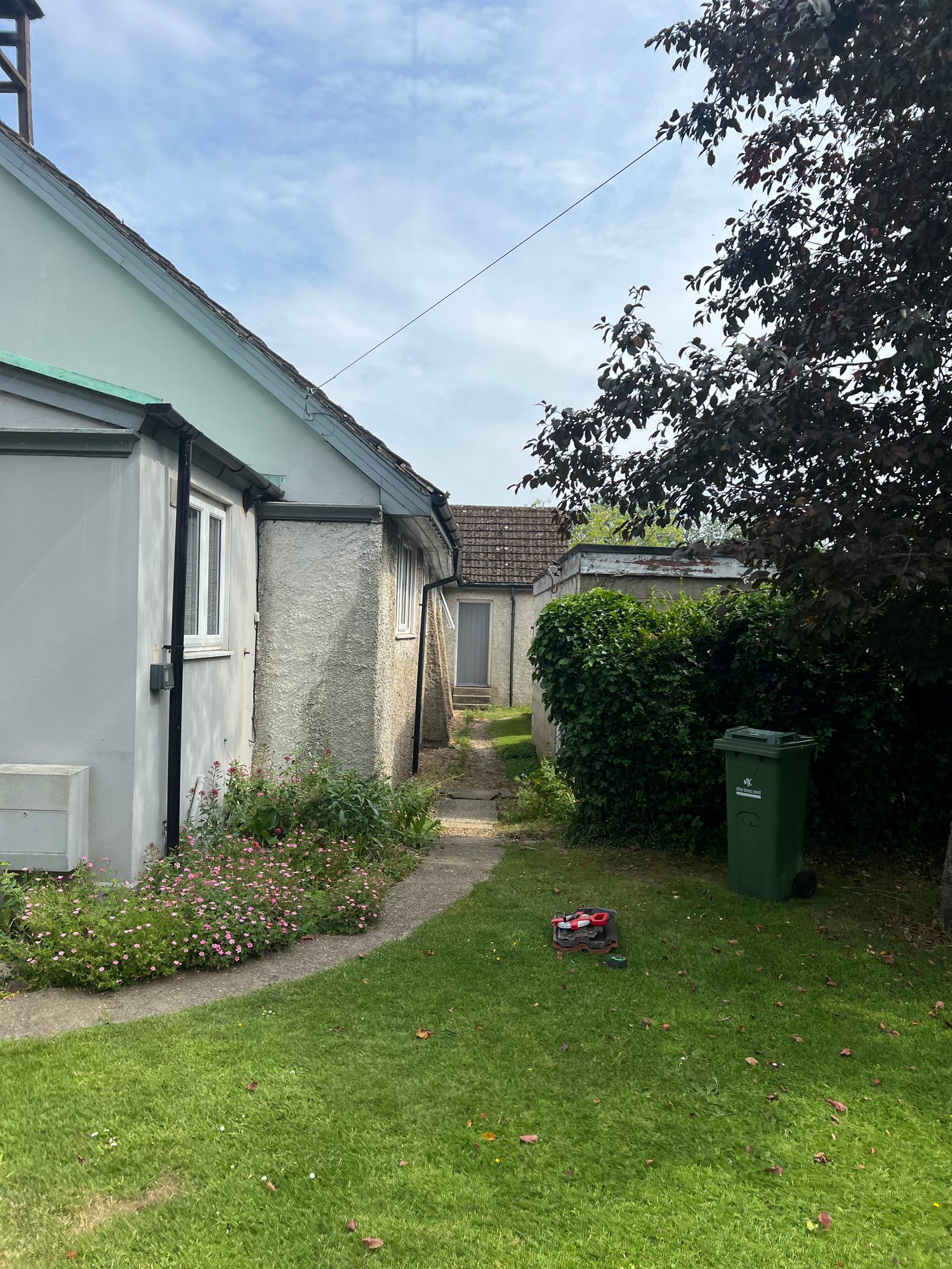 Side view of the church with rendered walls, windows, roofline and guttering, with a grassed garden and pathway alongside the building