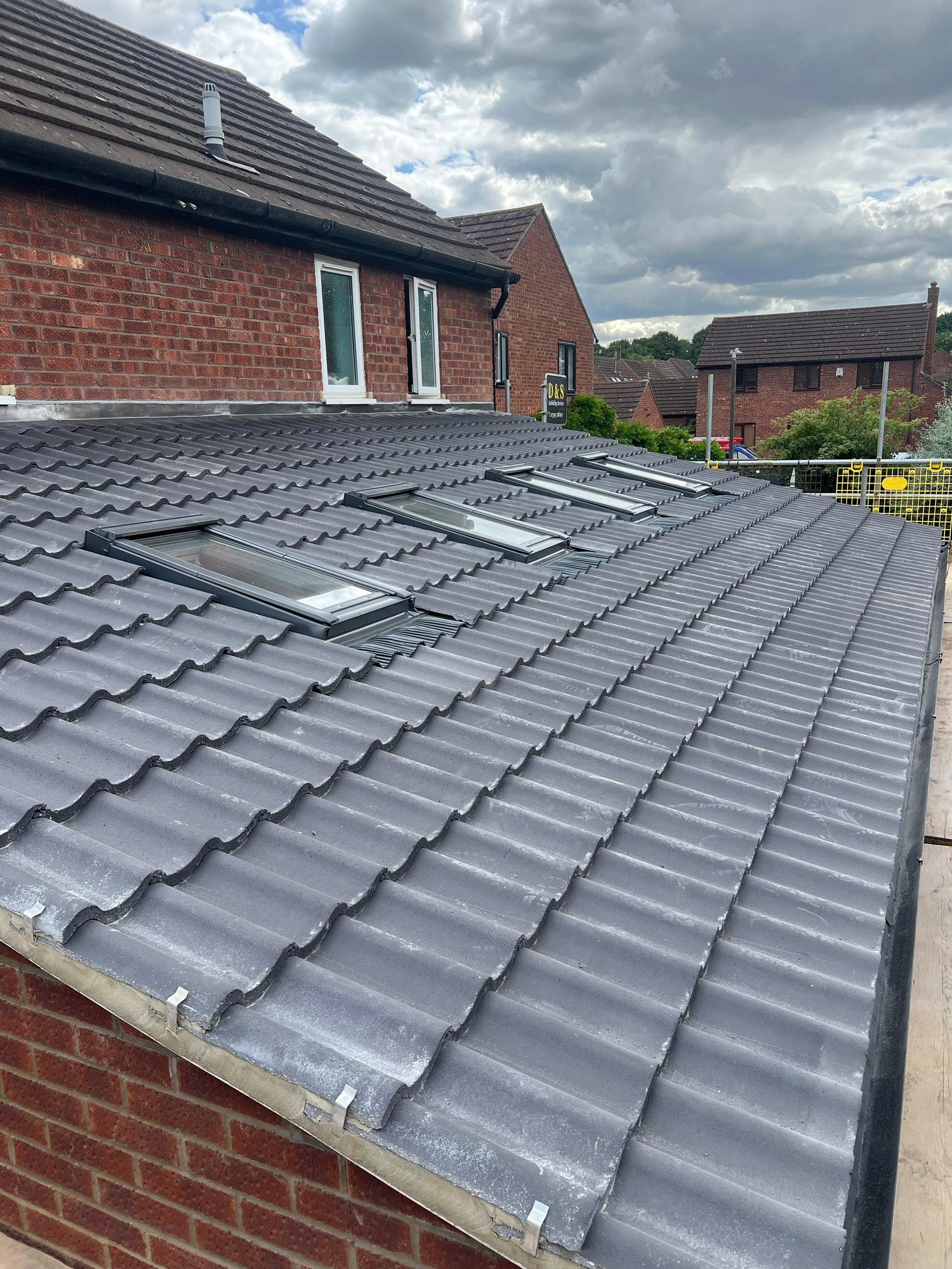 Completed extension roof showing grey tiled covering, multiple rooflights and guttering.