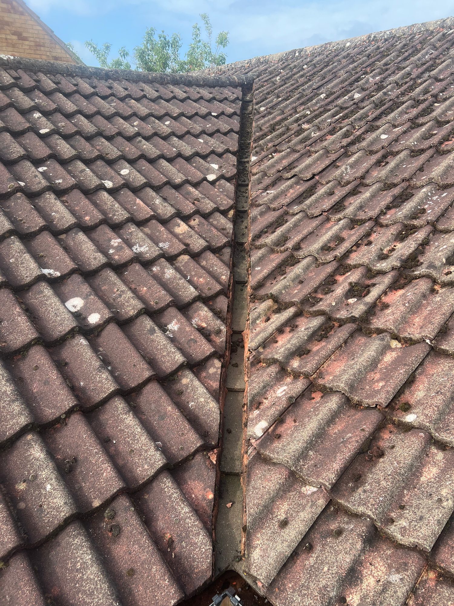 Close view of an existing tiled roof valley showing weathered and deteriorated valley detailing between two roof slopes