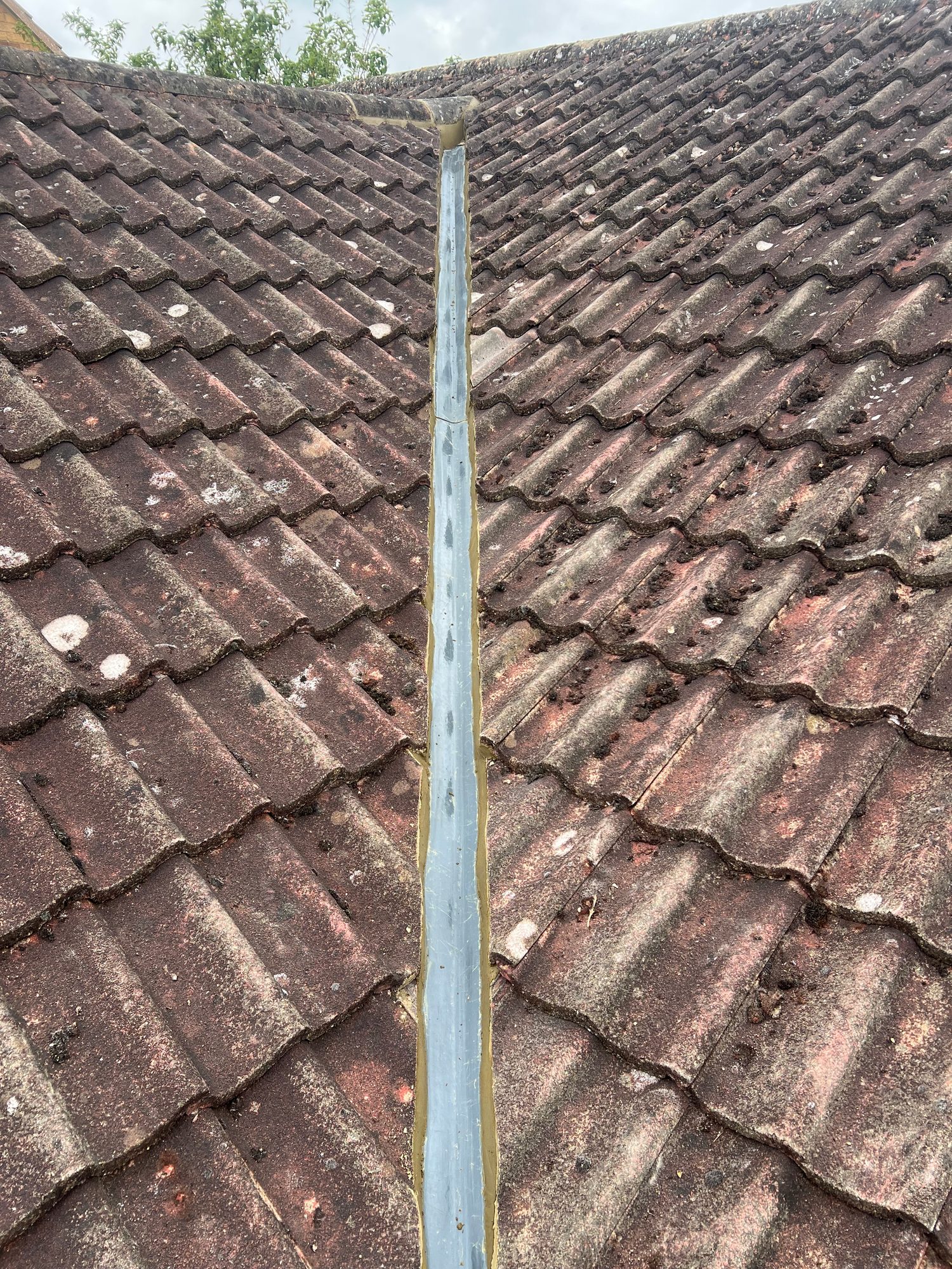 Completed roof valley with a new GRP valley channel installed between two tiled roof slopes, with the surrounding roof tiles visible on either side