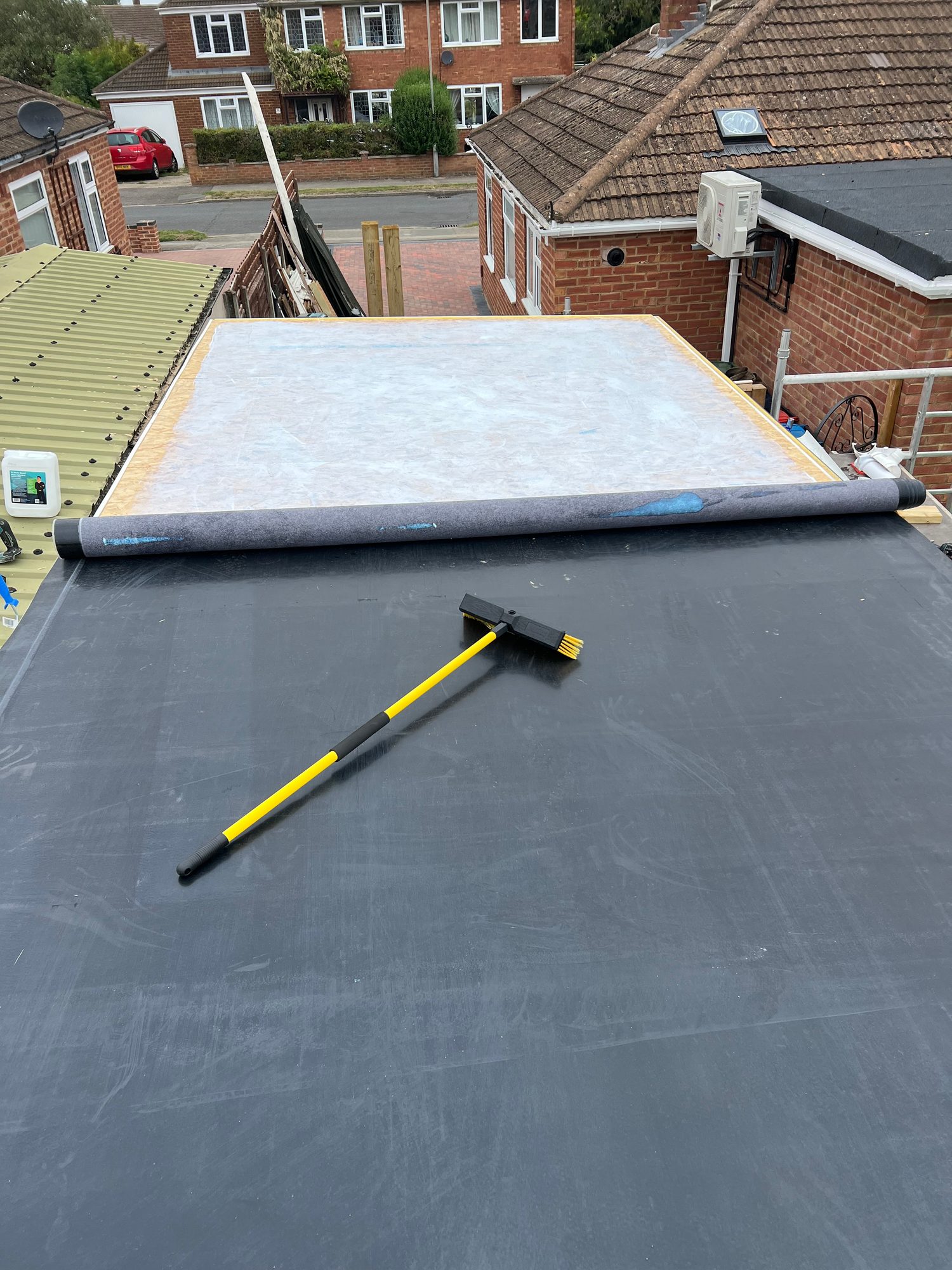 Roof membrane being positioned over the roof surface, with a rolled section of membrane