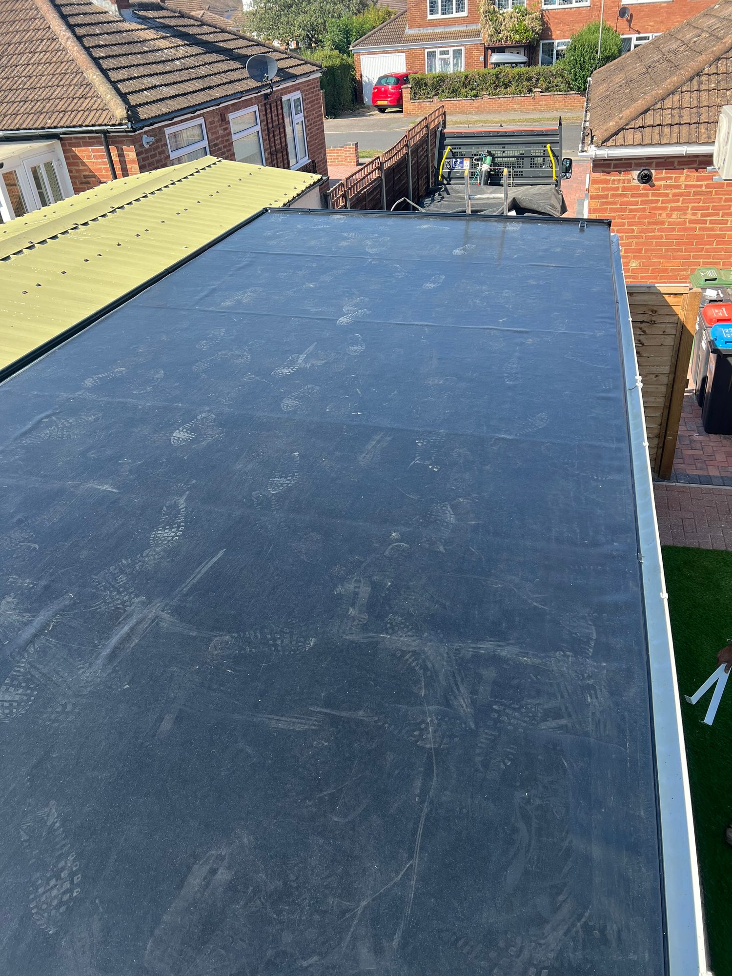 Completed flat roof with a dark membrane surface and finished perimeter edging, viewed from above