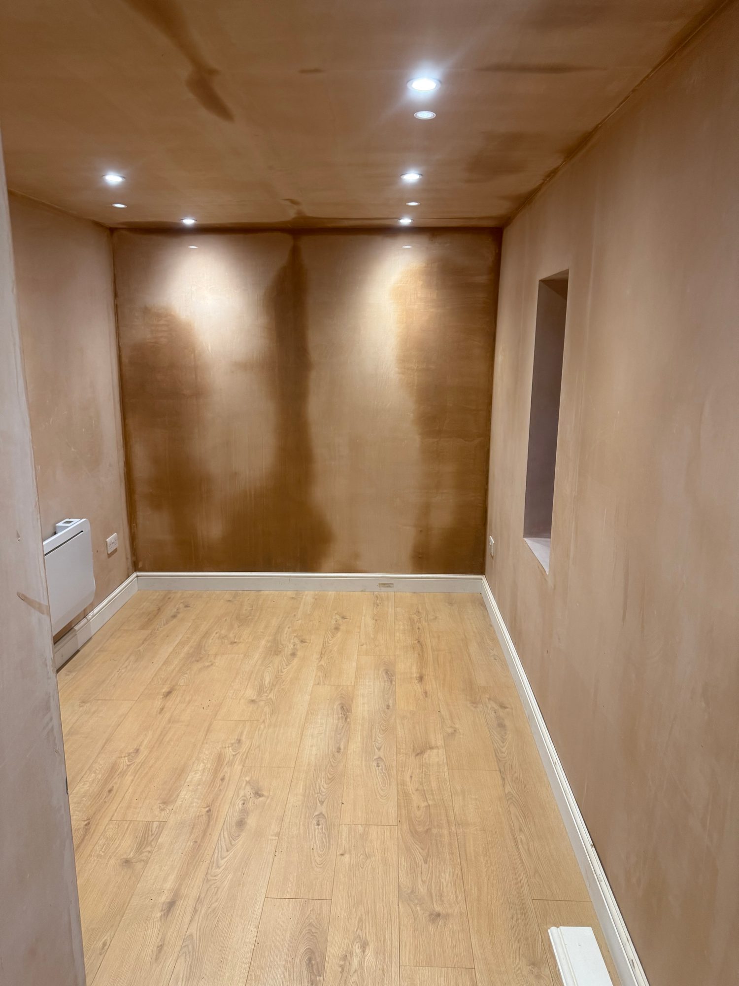 Finished interior room with wood-effect flooring, white skirting boards, plastered walls and multiple recessed ceiling lights