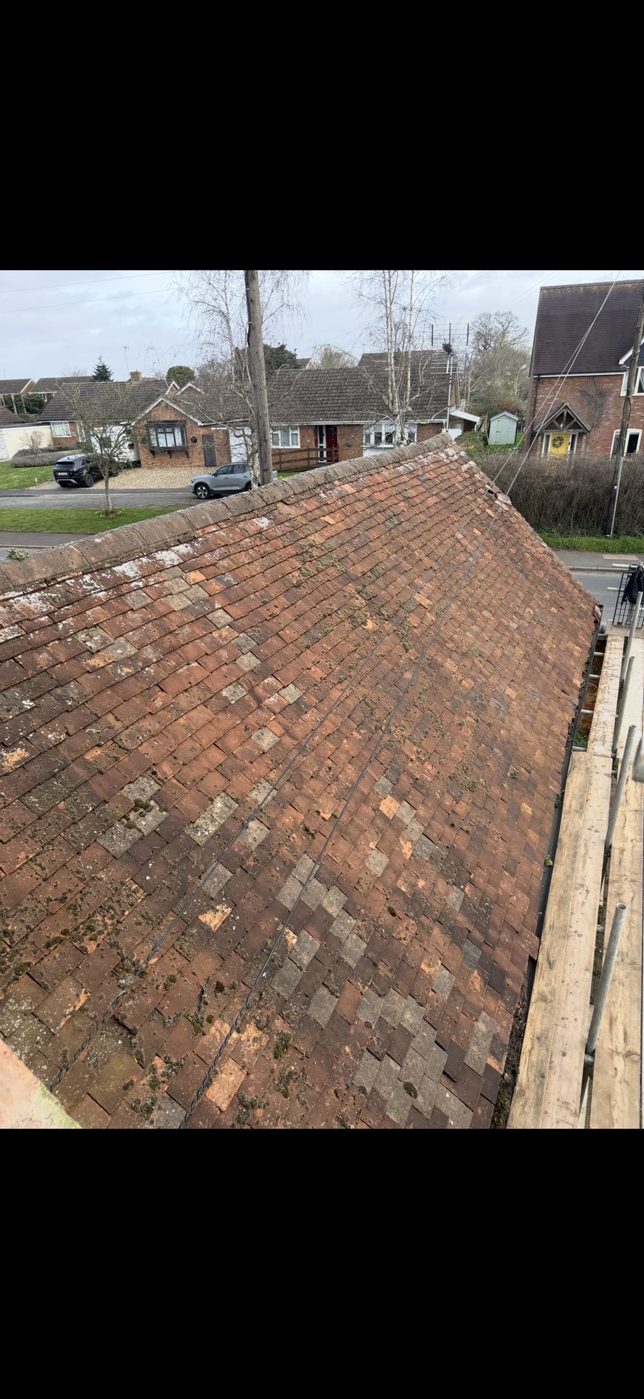 Large tiled roof covered with weathered, discoloured tiles and scattered moss growth