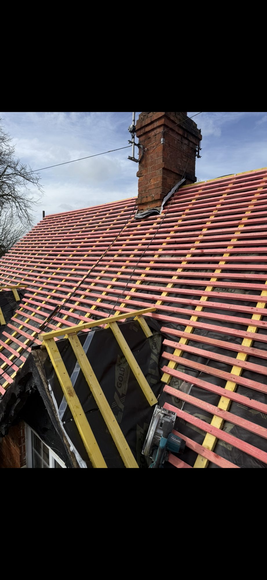 New roofing membrane and timber battens installed across the main roof around the chimney and window gable