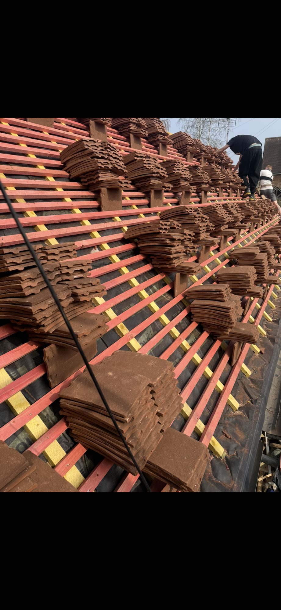Roof tiles arranged in stacks across the new battens while installation continues