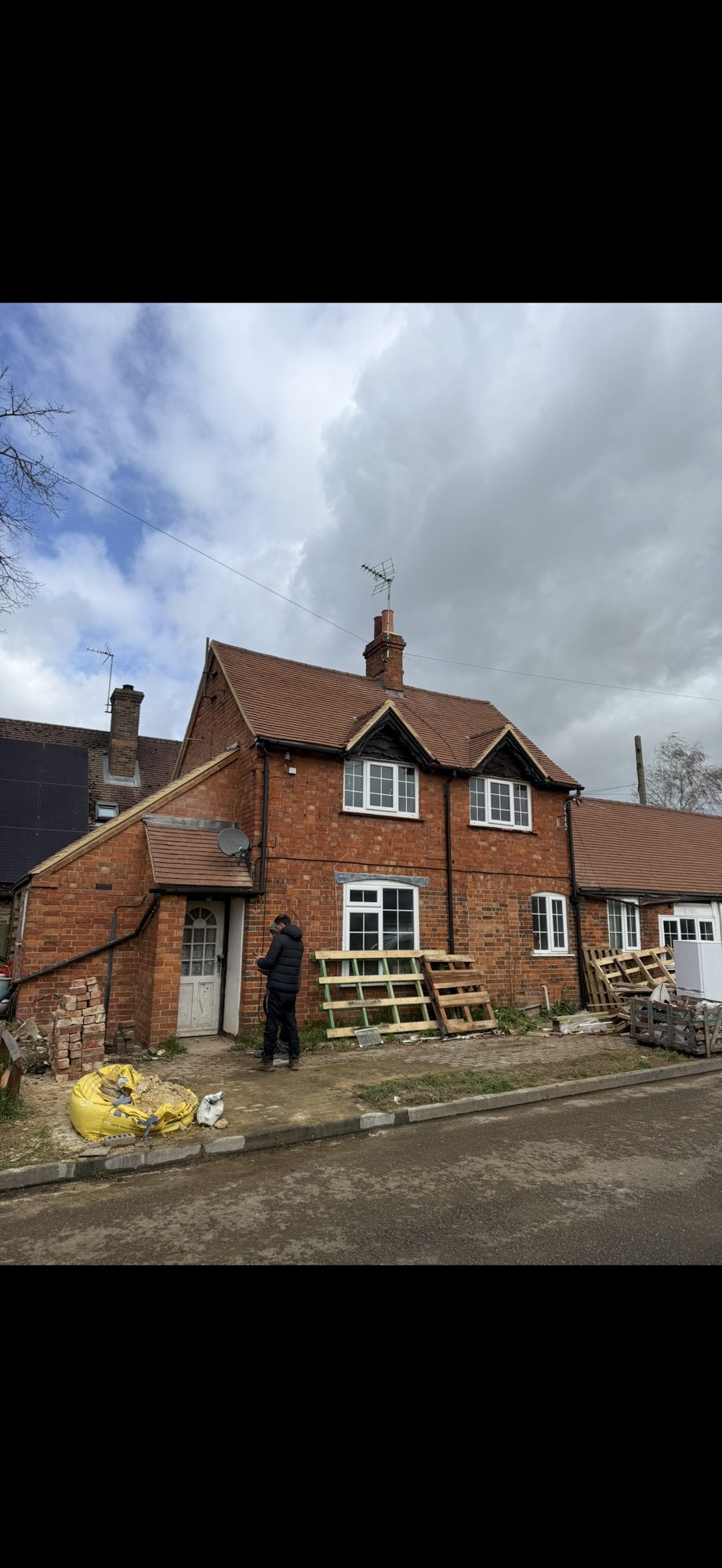 Period brick house with new roof tiles fitted around the chimney and projecting window gables