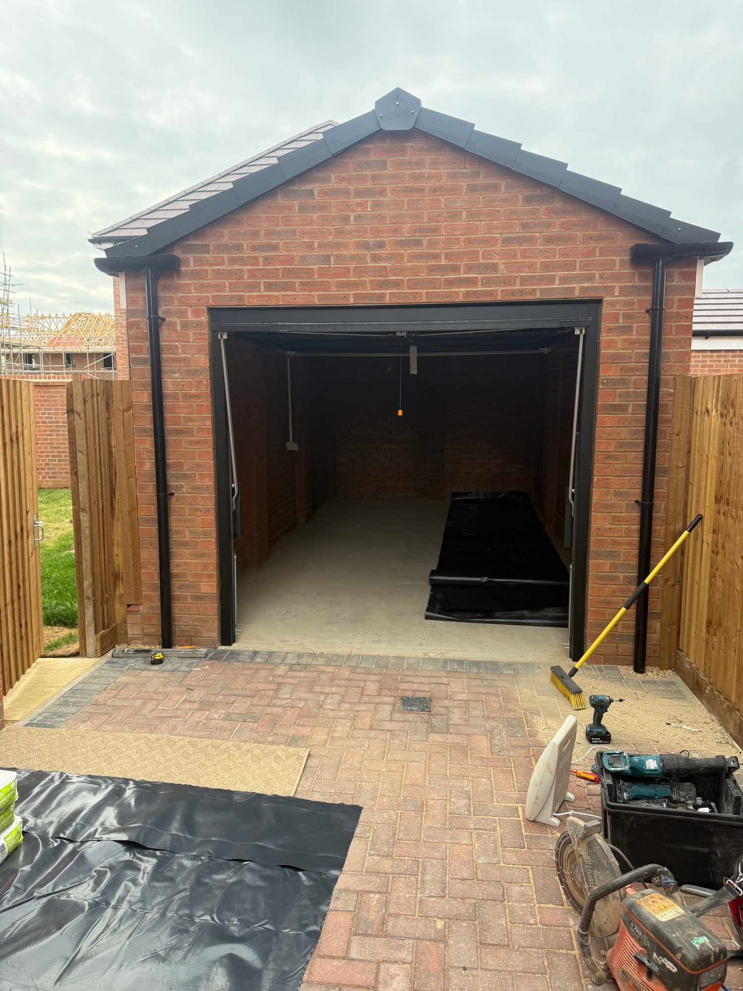 Original garage entrance with the main door open and construction materials positioned outside before the conversion