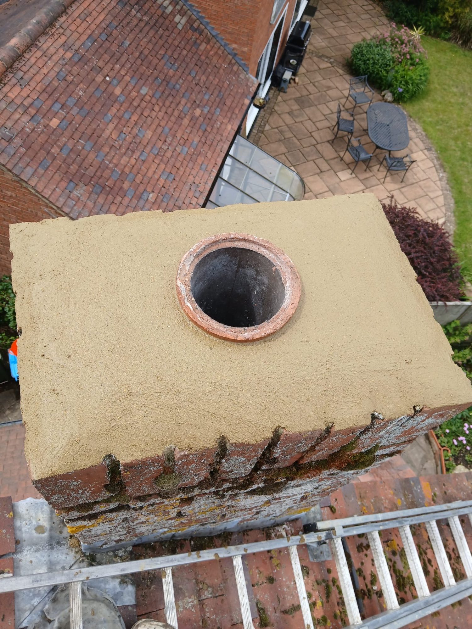 Close-up view of a circular chimney flue opening surrounded by a smooth mortar finish above weathered brickwork
