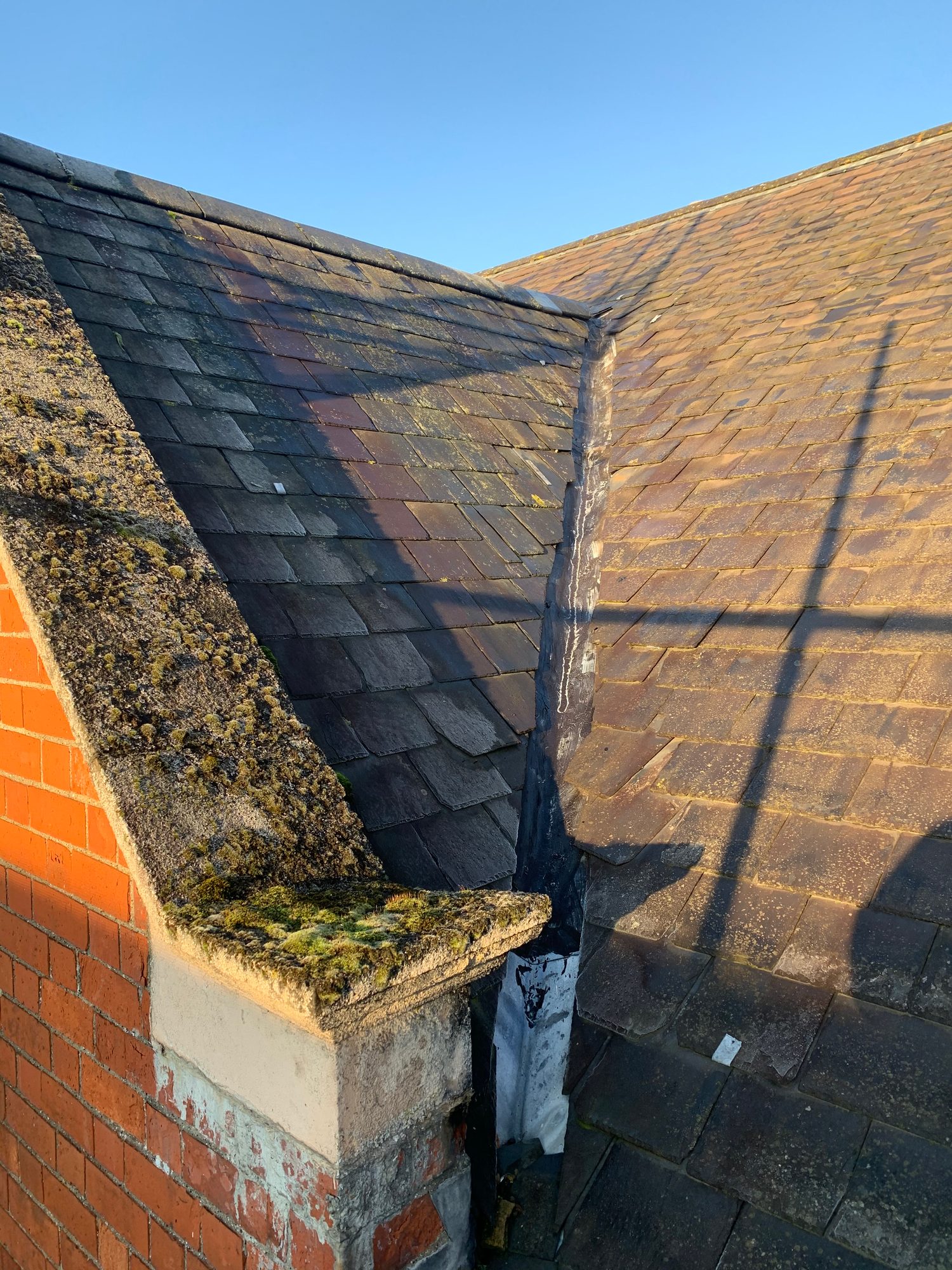 Before - The existing slate roof and roof valley showing weathering and moss before replacement works
