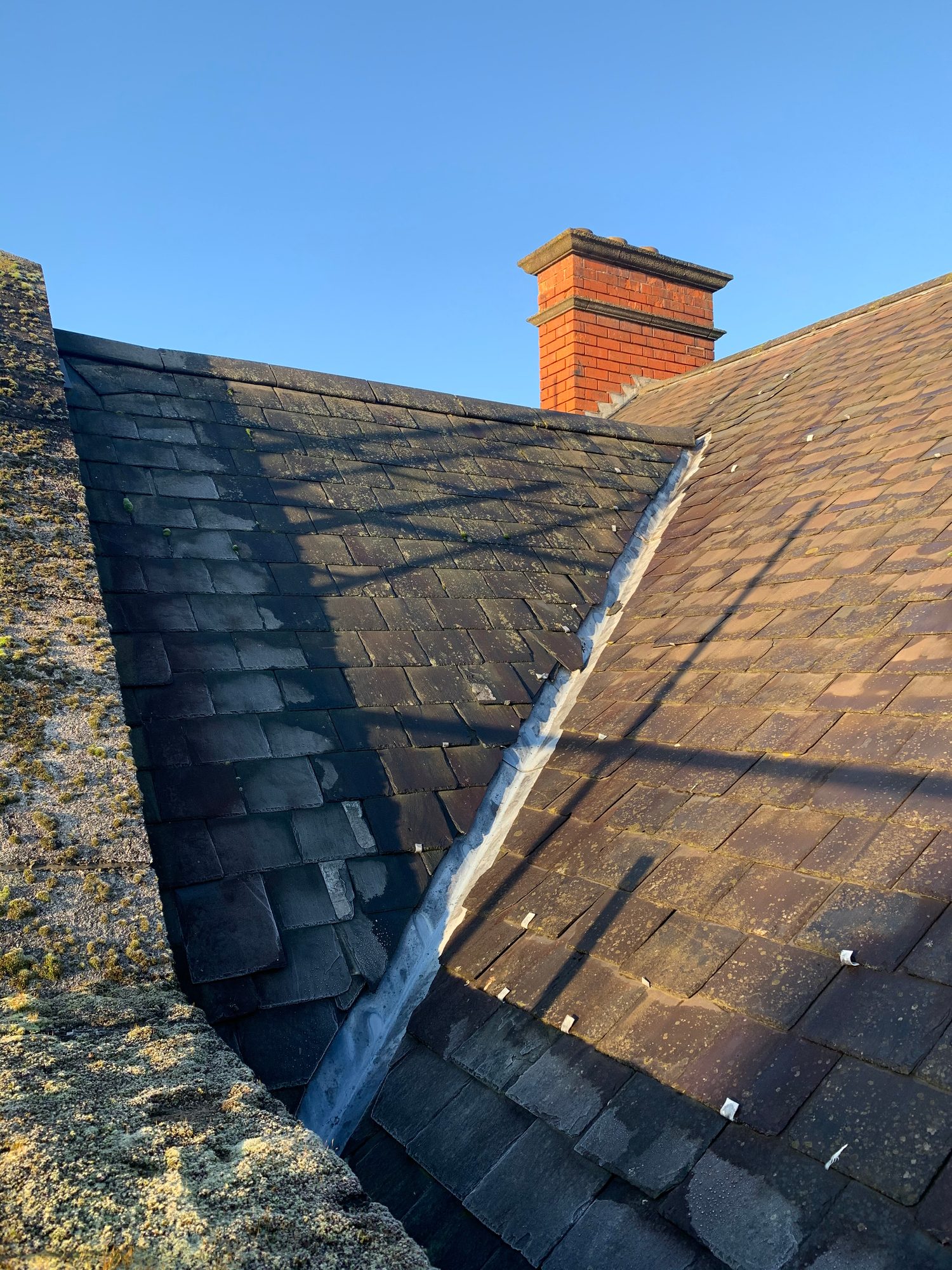 Before - The original slate roof and valley showing aged, weathered slates before the large roof replacement