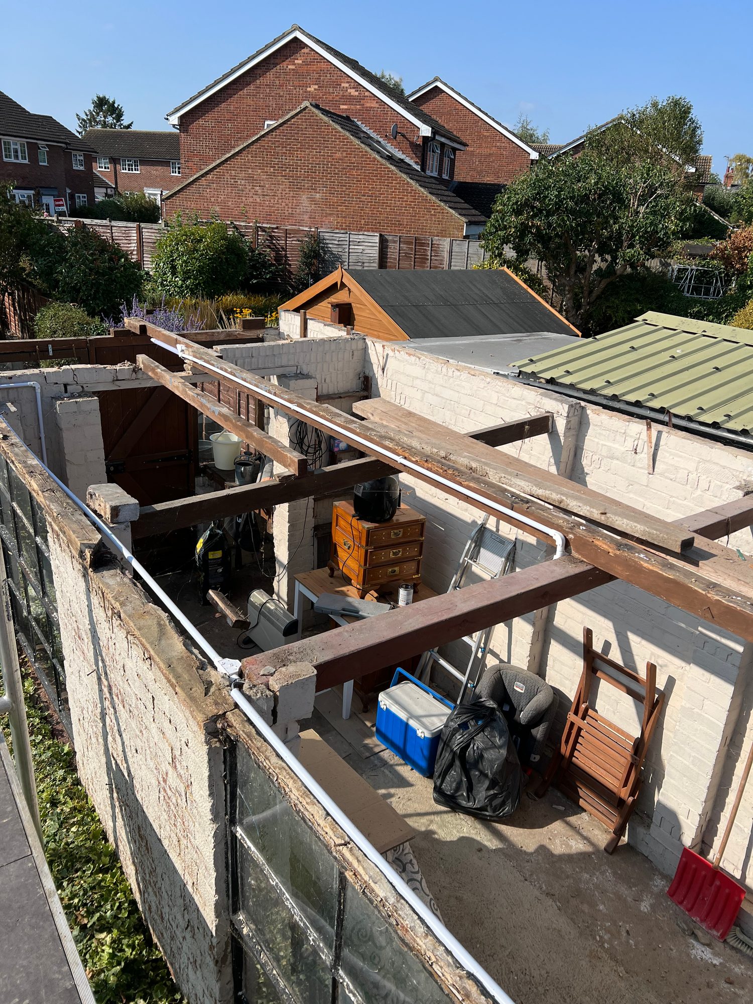 Partially opened roof structure showing exposed timber framing, roof joists and existing roof sections around the work area