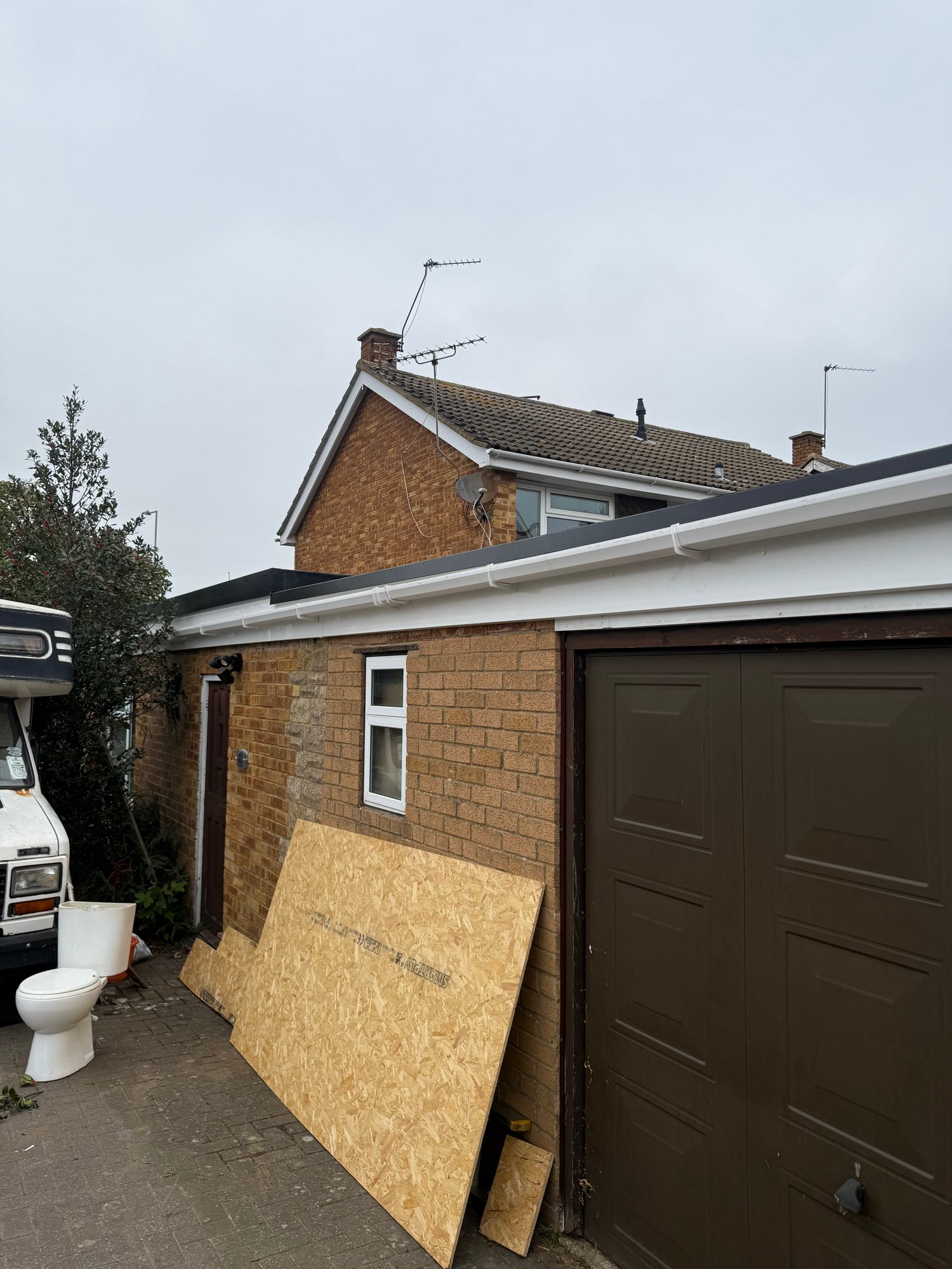 Completed flat roof with a finished roof edge and white guttering above the brick garage