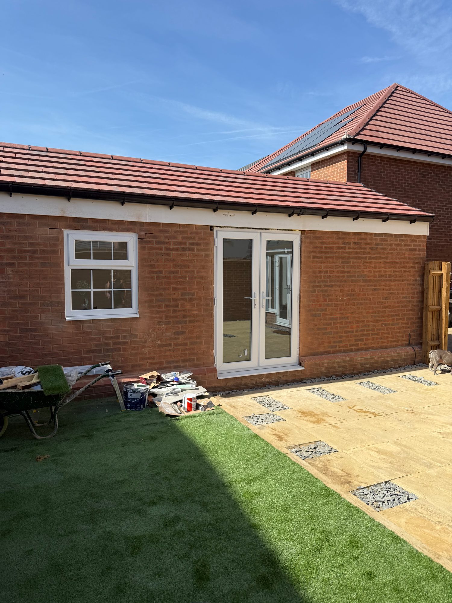 Completed brick exterior with a fitted window and glazed double doors opening onto the garden