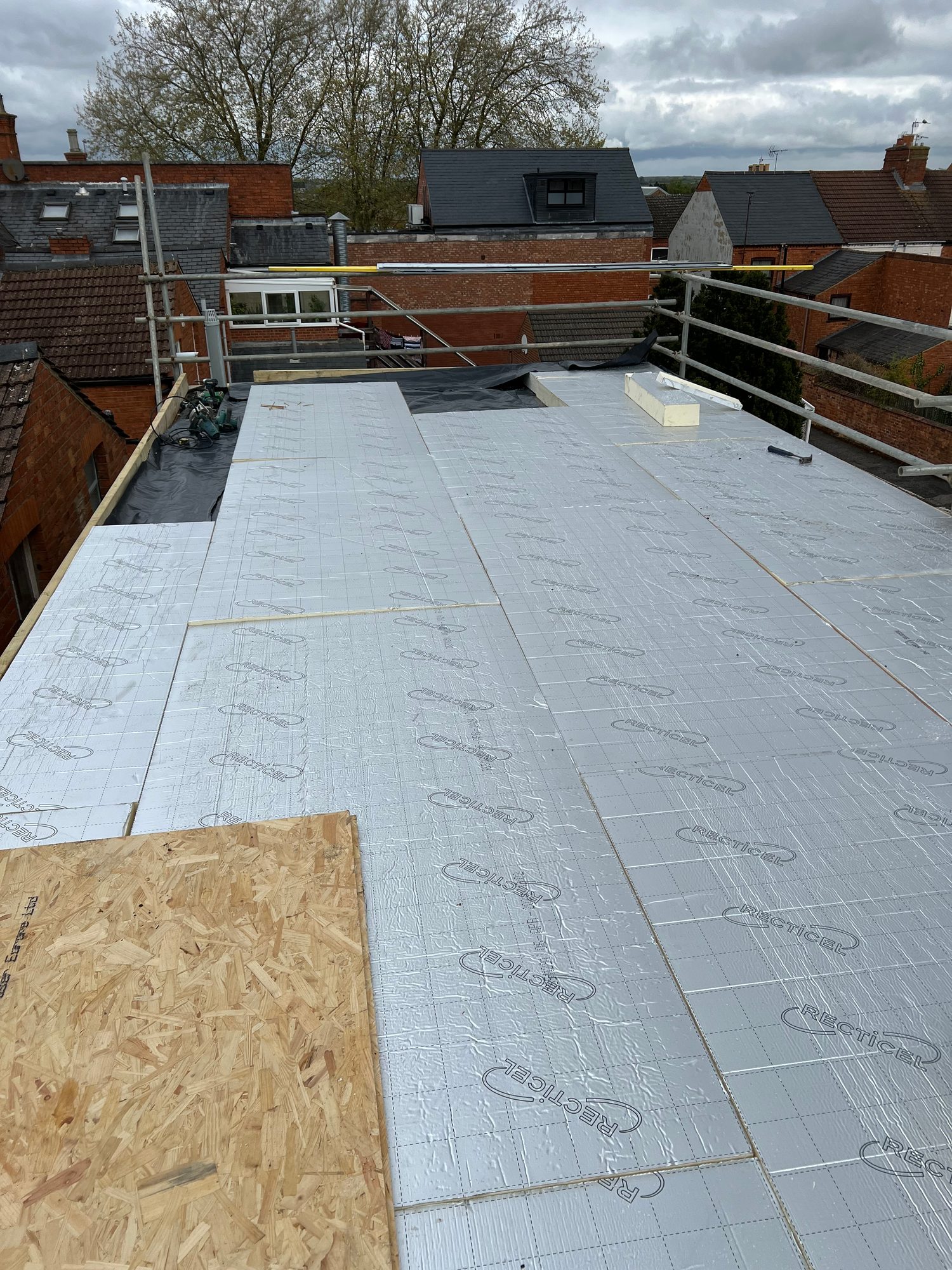 During - The flat roof during installation with rigid insulation boards being laid across the roof structure