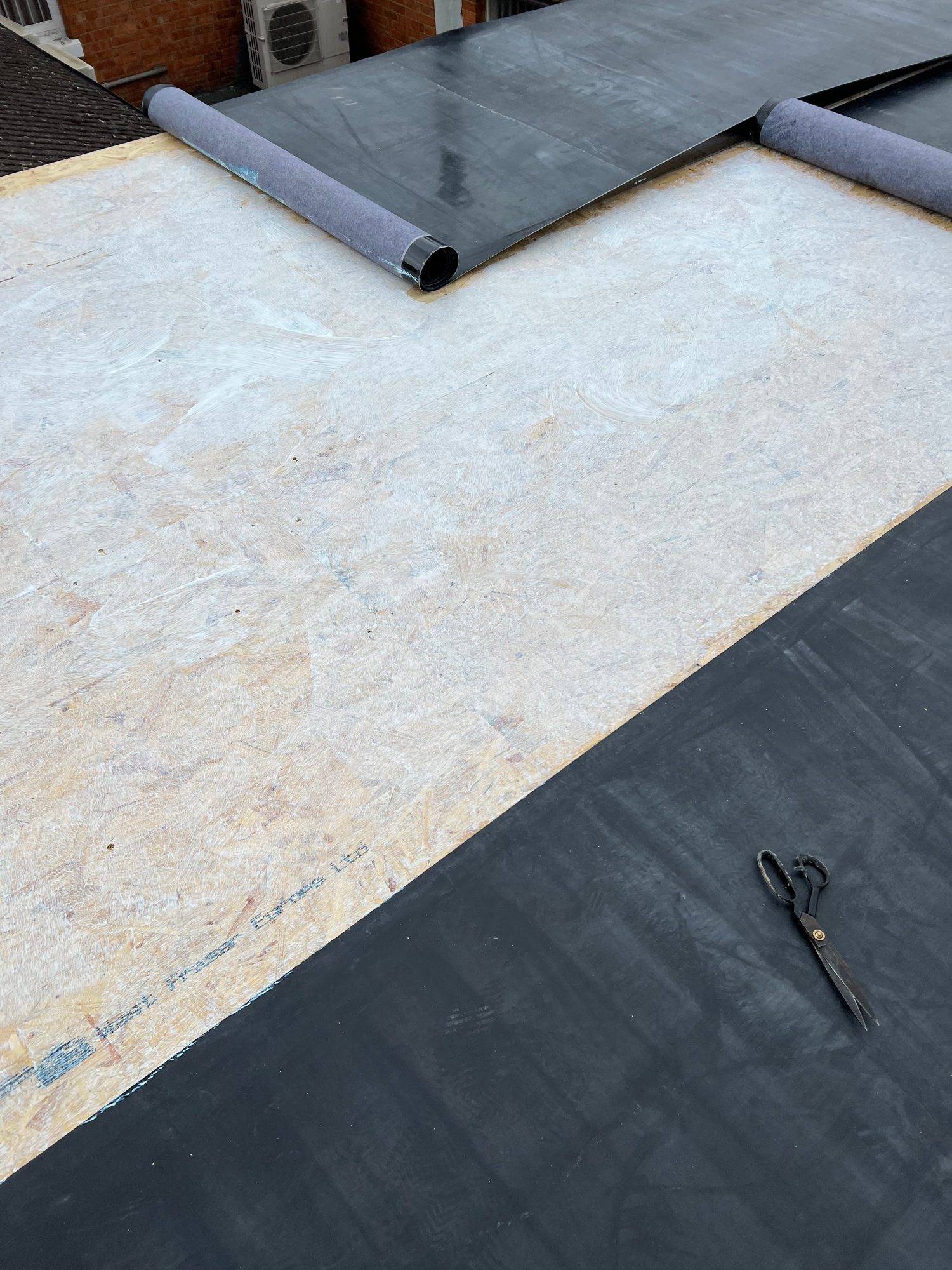 During - The flat roof during installation with sections of the roofing membrane being bonded to the timber decking