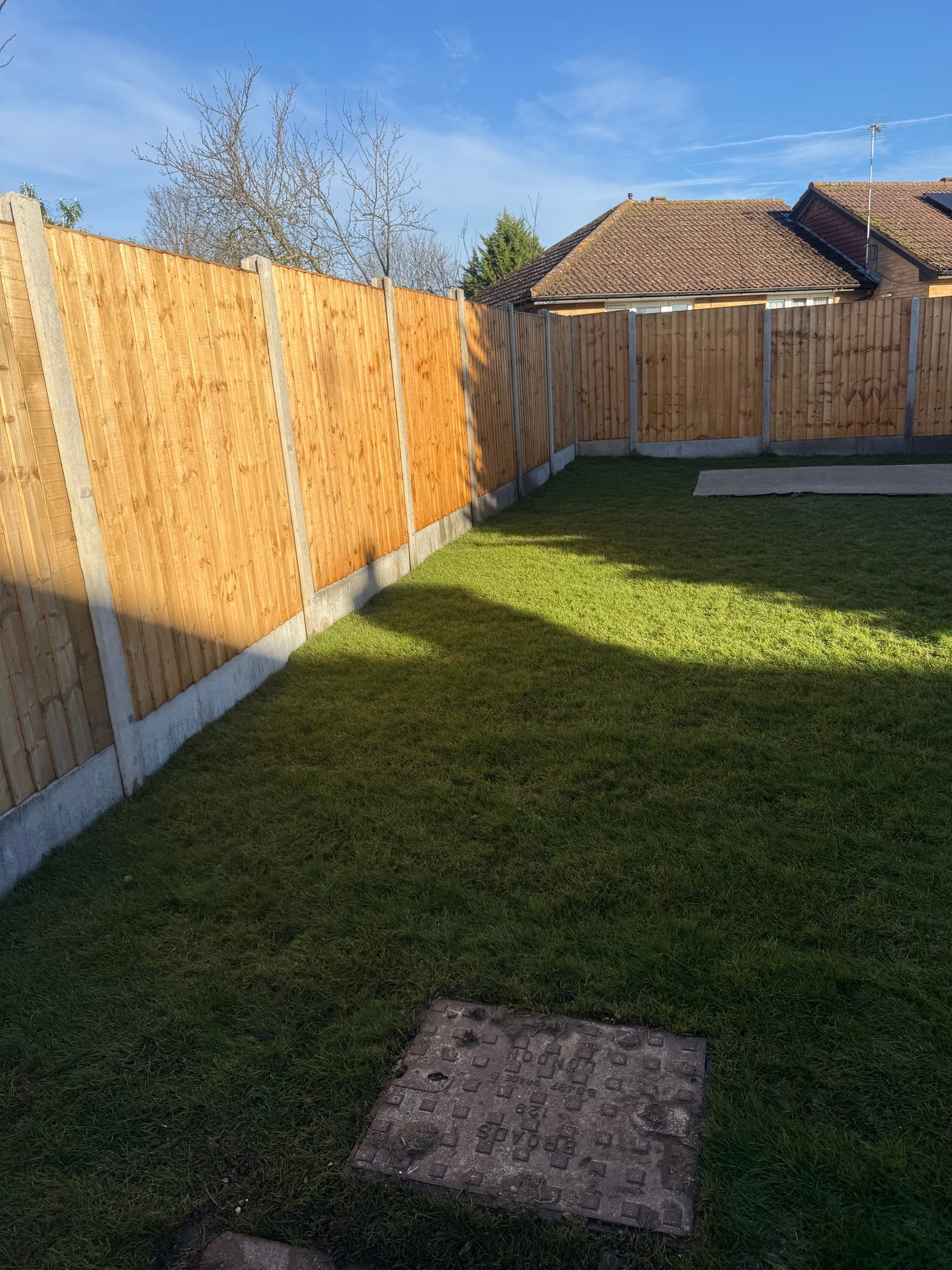 Completed rear garden with fresh turf and new timber fence panels supported by concrete posts